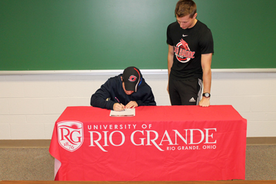 Rio assistant coach Steve Gruenberg watches as Oak Hill's Tim Haag signs with the RedStorm